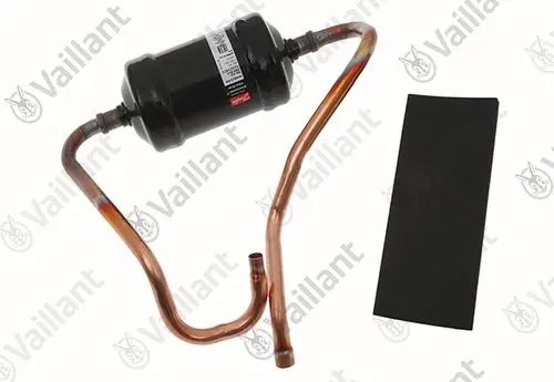 Vaillant Filtertrockner mit kupfernen Rohrleitungen und einem schwarzen Behälter, auf einer neutralen Oberfläche platziert.
